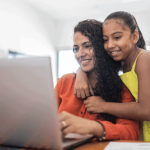 A mother and daughter explore school choice options on a laptop.
