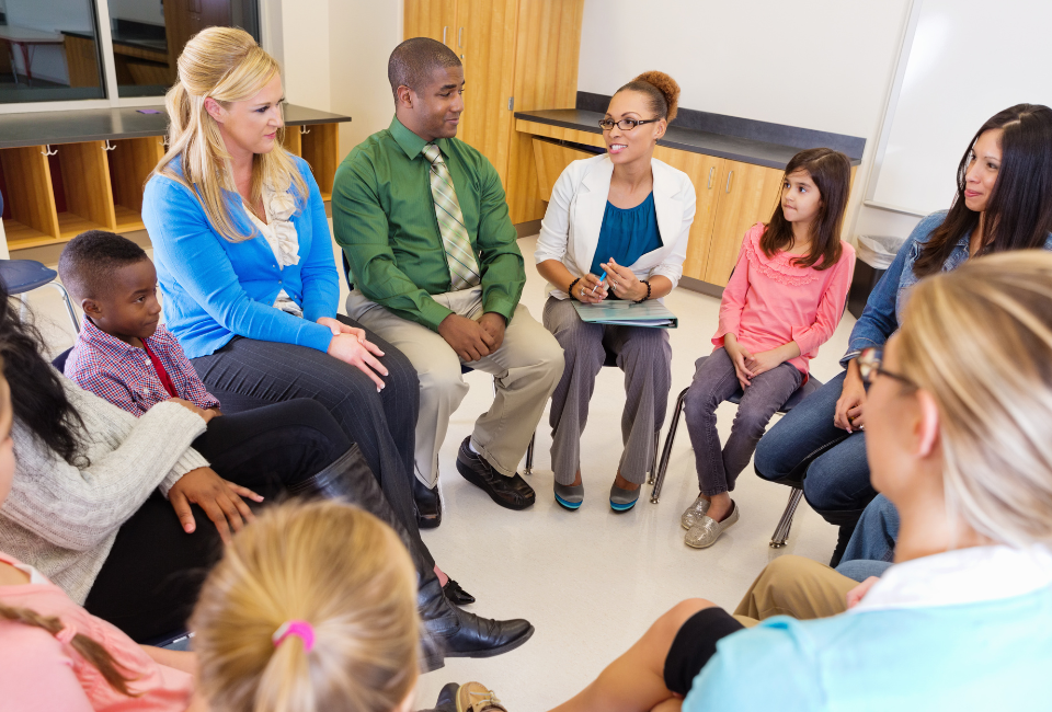 a group of families and educators sit around in a circle for an informational school session