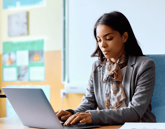 Female educator working on a laptop in the classroom