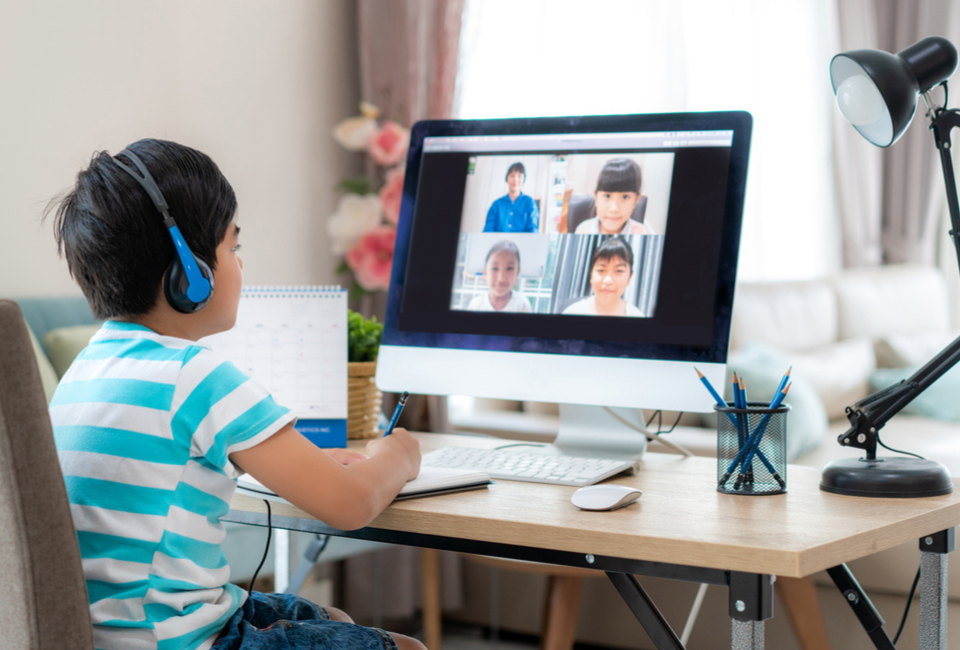 A young student joins his class virtually in a synchronous classroom setting. 