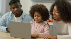 Parents sit with their daughter at a laptop to research school choice programs in their area.
