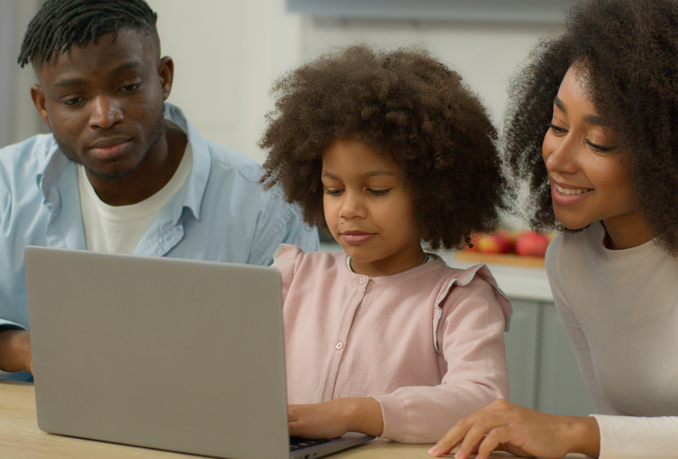 Parents sit with their daughter at a laptop to research school choice programs in their area.