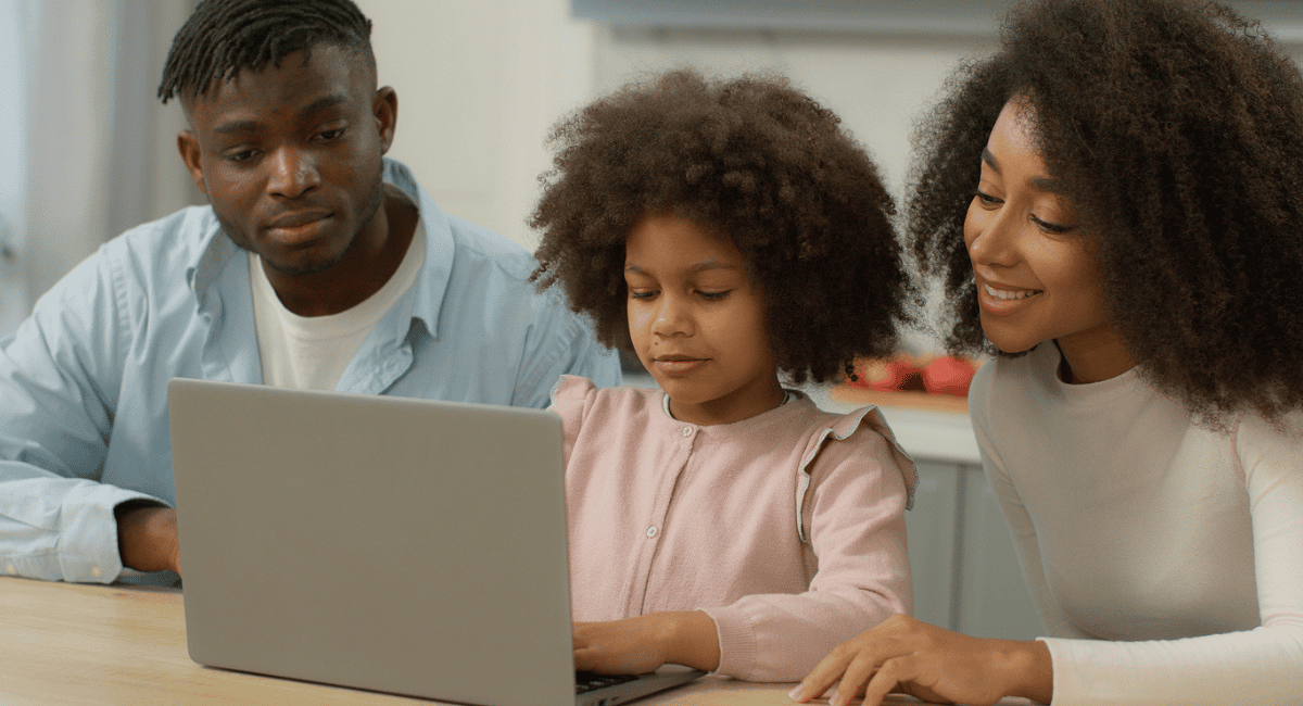 Parents sit with their daughter at a laptop to research school choice programs in their area.