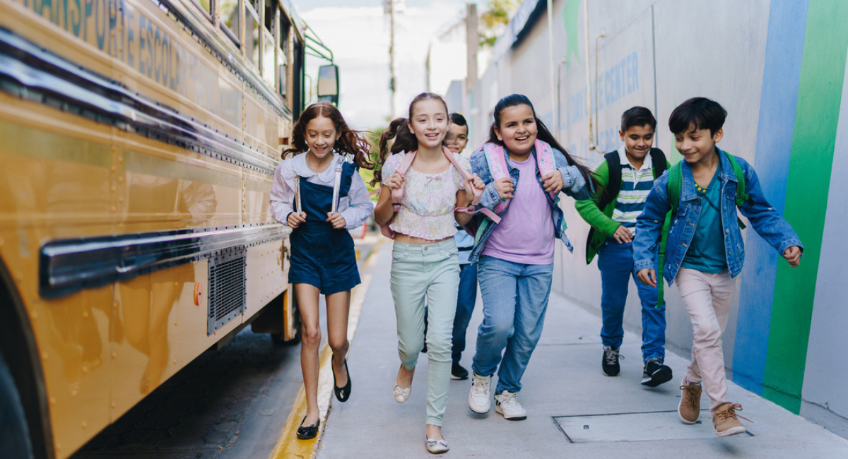 Excited children run off the bus to enter school for the first day of back to school.