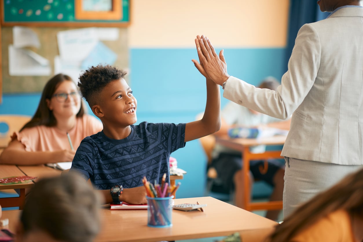 A happy student high-fives his teacher after a successful enrollment process.